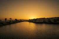 Serene sunset view over a resort and calm water, reflecting warm golden tones.