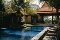 Relax by a luxurious tropical pool surrounded by lush palm trees under a sunny sky, perfect for summer getaways.