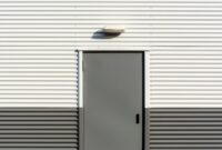 Minimalist image of a corrugated metal wall with a centered door, showcasing industrial architecture.