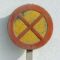 Rusty no parking sign with yellow and red colors mounted on a white wall, showing visible wear and texture.