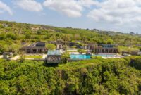 Aerial view of a luxurious villa with an infinity pool on a cliffside in Bali, Indonesia.