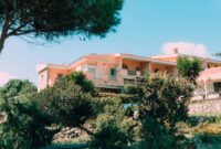 Villa Alba Luxury Mediterranean Villa With Stunning Architecture Charming Mediterranean villa nestled in vibrant, lush gardens under a clear blue sky.